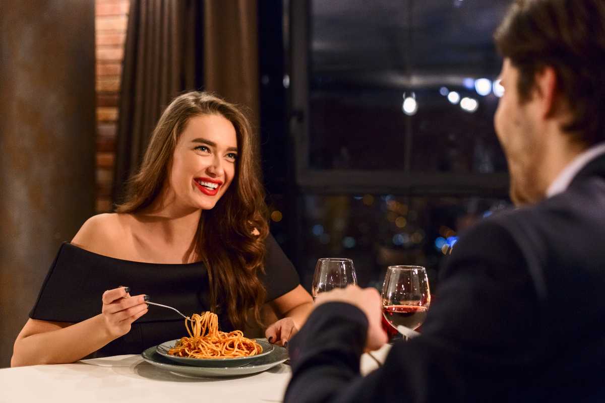 Scorcio di un tipico ristorante toscano con tavoli di legno, vino rosso, pane rustico e vista sulle colline di Montalcino