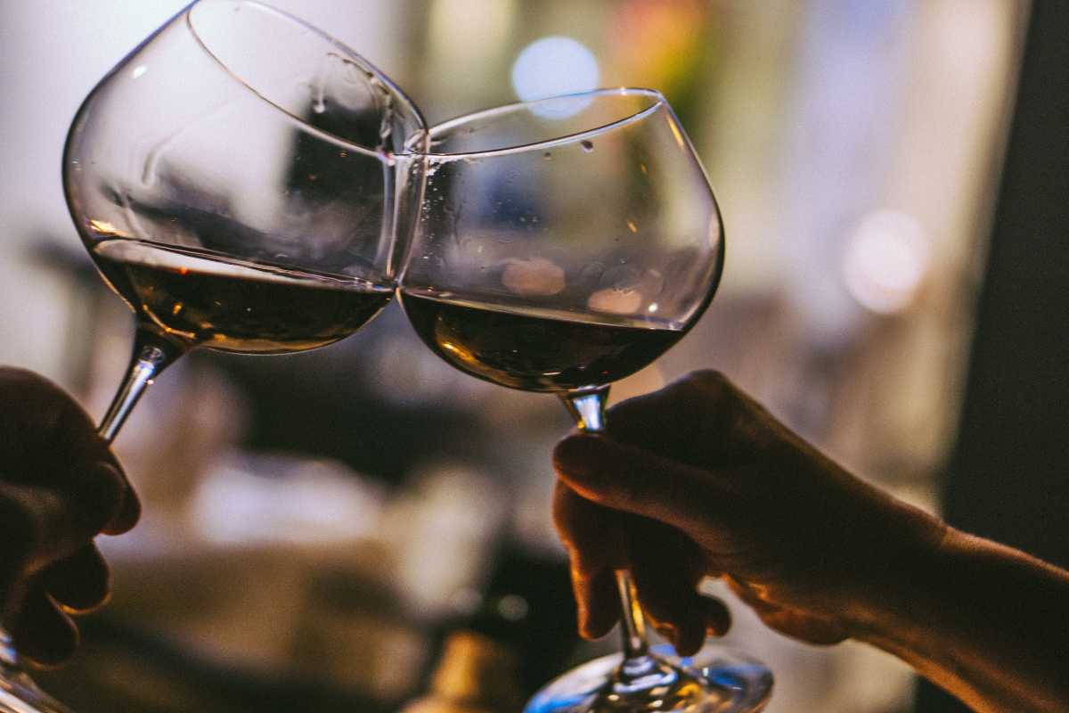 Degustazione di vini in una cantina storica di Montalcino, calici di Brunello sul tavolo in legno, atmosfera conviviale e dettagli architettonici toscani
